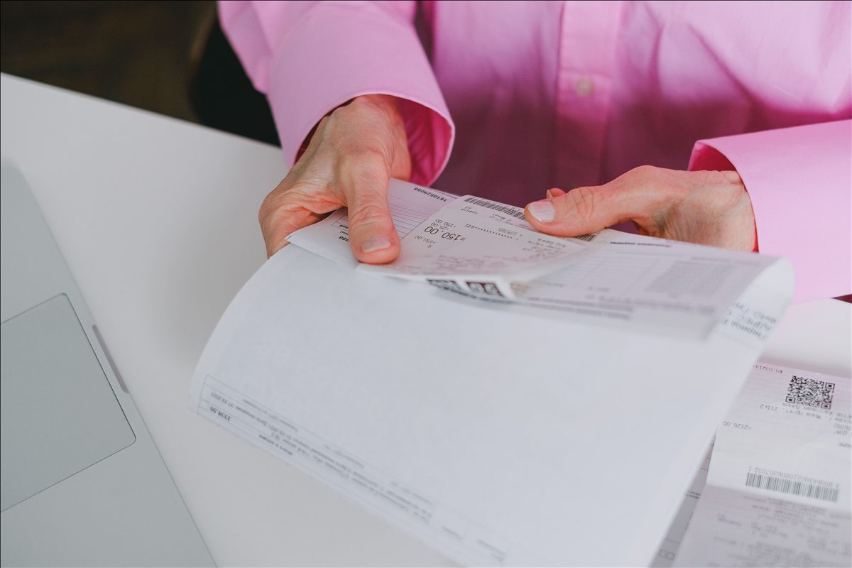 Przedsiębiorczyni przegląda papierową fakturę przy laptopie